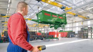 Crane operator using a Demag v-girder crane with tandem hoists and a DRC10D3 radio transmitter.